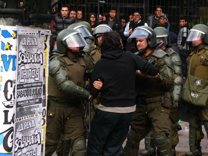 Fotografía documental de Carabineros trasladando a una persona durante una protesta estudiantil en Chile, 2011. Autor: Nicolás15, CC BY-SA 3.0.