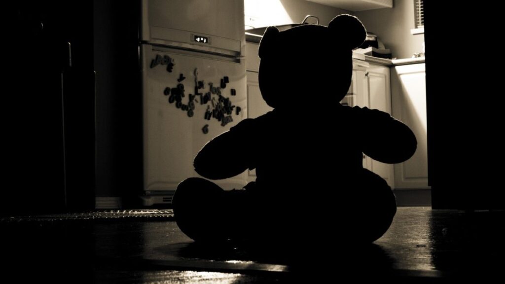 Imagen referencial: oso de peluche entre sombras, símbolo de la vulnerabilidad infantil frente a la violencia.